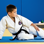 Child Learning Basic Judo**

A young boy (6-7 years old) in a white judogi, practicing a forward roll on a blue tatami mat. An experienced, friendly-looking male coach is demonstrating the technique. The dojo is bright and clean, with motivational posters on the walls. Focus on developing coordination and flexibility. safe for work, appropriate content, fully clothed, modest, family-friendly, perfect anatomy, correct proportions, natural pose, well-formed hands, proper finger count, natural body proportions.

**